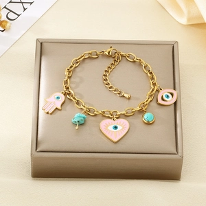 Detail eines Goldkettenarmbands mit rosa Emaille-Herz und blauen Evil Eye Anhängern