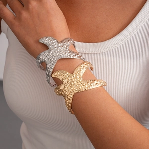 Detailed macro view of gold and silver starfish cuff bracelets with realistic beaded texture
