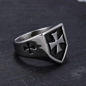 Close-up of vintage stainless steel shield ring with cross relief on rock background