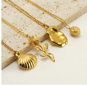 Detailed close-up of four gold stainless steel necklaces with rose and shell pendants
