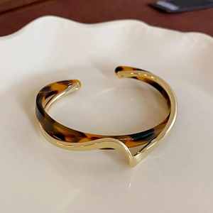 Bracciale rigido aperto minimalista con intreccio in metallo dorato e tartarugato
