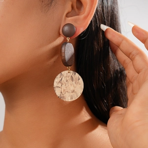 Close-up of geometric acrylic leopard print earrings with wooden sphere on model