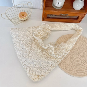 Close-up of daisy lace embroidery and ruffled handle on this cream canvas tote bag