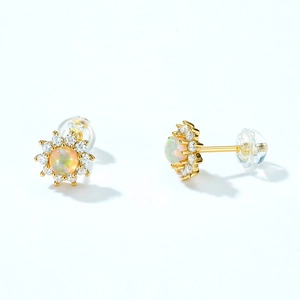 Close-up of star stud earrings with central opal stone and small zircon accents
