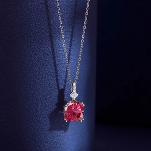 Macro shot of a pink gemstone necklace pendant on a refined silver chain over blue background