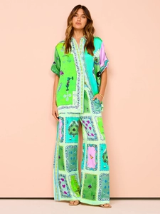 Detail of silk-like two-piece set with vibrant green artistic prints and wide-leg trousers