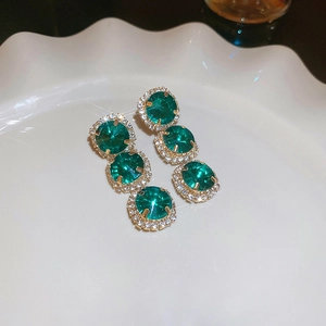 Close-up of green crystal flower earrings with gold plating and sparkling zircons