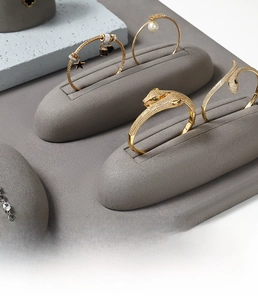 Macro detail of luxury gold-plated bracelets with zircon inlay on grey velvet stand