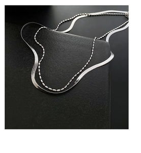Detailed macro view of silver double-layer necklace with ball chain and herringbone chain