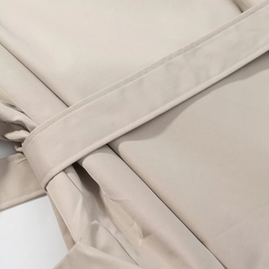 Close-up of the waist belt tie and stitching details on a beige trench coat