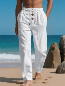 Detail of white linen trousers with elastic drawstring waist and decorative buttons