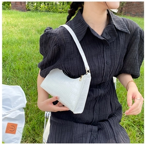 Detailed macro view of white crocodile pattern embossed underarm bag with gold metal zipper