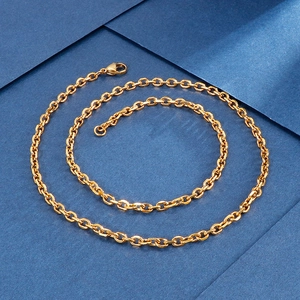 Detail of a golden stainless steel O-chain necklace with a lobster clasp on blue paper