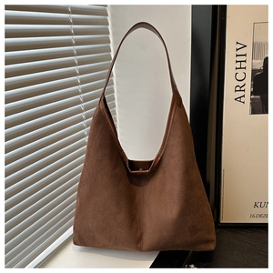 Brown suede tote bag placed by window with soft shadows for a minimalist aesthetic