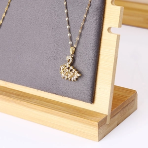 Golden swan pendant necklace with white crystals on a bamboo jewelry display stand