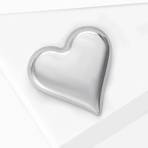 Macro shot of minimalist silver heart brooch on white pedestal for elegant suits