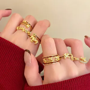 Detail of vintage gold-plated horse ring and enamel coins worn on a hand with red sweater