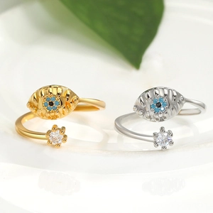 Dettaglio di anelli regolabili malocchio in oro e argento con pietre blu incastonate