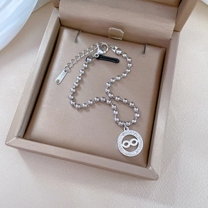 Detailed macro of stainless steel infinity charm bracelet with beaded chain in a jewelry box