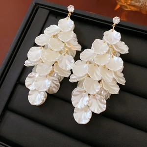 Dettaglio macro di orecchini a petalo bianchi con accenti dorati e cristalli brillanti