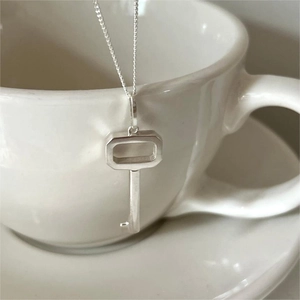Elegant 925 sterling silver key pendant necklace hanging on white ceramic coffee cup