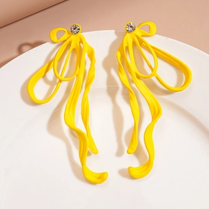 Detail of yellow wave ribbon earrings with sparkling rhinestone on white plate