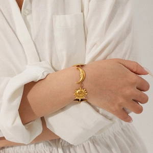 Close-up of a 18K gold star moon sun bracelet on model wrist for beach style