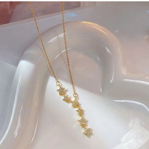 Detail of gold star pendant necklace with six cubic zirconia stars on a heart dish