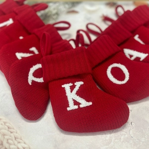 Red knitted Christmas stockings with white letter embroidery for holiday tree decoration