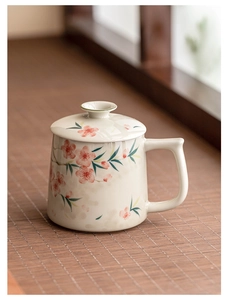 Close-up of hand-painted peach blossom ceramic mug with lid in a soft natural light setting