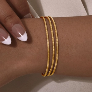 Macro view of triple-layered golden snake chain bracelet on a model's wrist