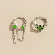 Detail of silver rings featuring green heart tassels and checkered crystal pattern