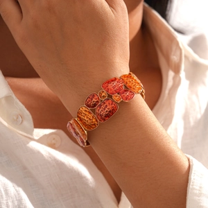 Detail of wide geometric stretch bracelet with hammered orange enamel and gold finish