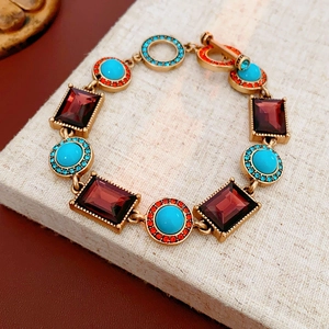 Detailed view of a vintage gold bracelet with red gems and turquoise on burlap