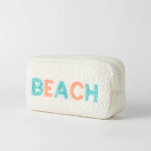 Close-up of white sherpa cosmetic bag with colorful BEACH towel embroidery and zipper
