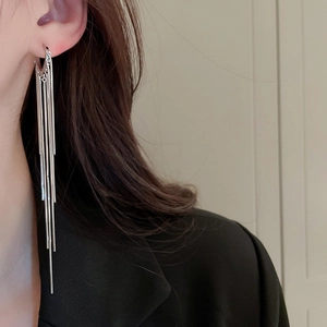 Close-up of elegant silver long tassel earrings worn by a model in a black suit