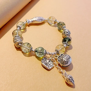 Detail of beaded bracelet with green crystal beads and silver fish-shaped pendants