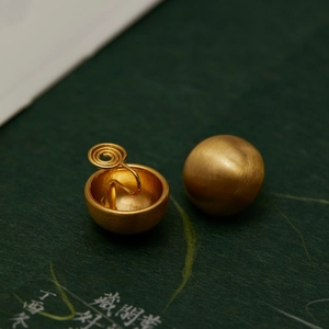 Macro detail of matte gold spherical clip-on earrings with sandblasted metal texture