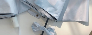 Detail of light blue sun umbrella with white cloud patterns and silk bow accessory