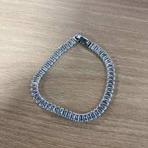 Macro shot of silver tennis bracelet featuring rectangular cubic zirconia in pave setting