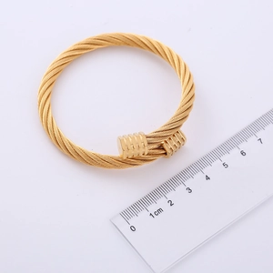 Detailed macro view of gold-plated stainless steel cable bracelet with industrial ends
