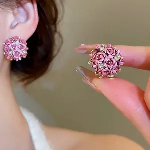 Pink rose ball earrings with crystals and silver needles shown on a model's ear