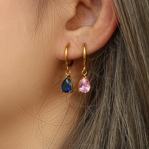 Détail de créoles dorées avec pendentifs en zircone bleu et rose en forme de poire