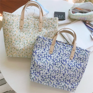 Floral canvas tote bags with leather handles and rivets on a desk with daily essentials
