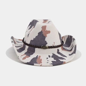 Detail of western cow print hat featuring braided leather band and metal bull emblem