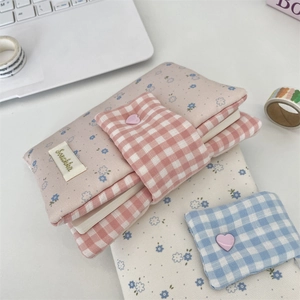 Detail of floral fabric book cover with heart button and pink plaid buckle strap