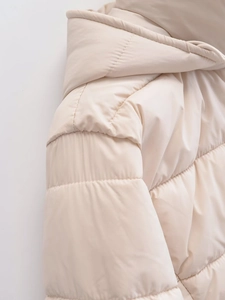 Macro detail of the shoulder seams and hood on a beige padded winter coat for women