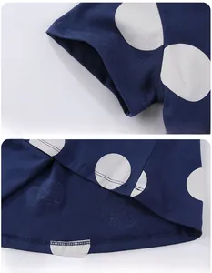 Détails des coutures sur les poignets et l'ourlet du haut en coton bleu marine à pois