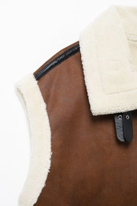 Detail view of brown suede vest showing soft white faux fur lining and leather trim