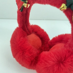 Close-up of red plush earmuffs with festive golden bells and satin bow decorations